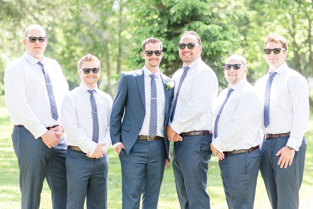 Groomsmen in navy blue suits pose for picture at Vickers Park