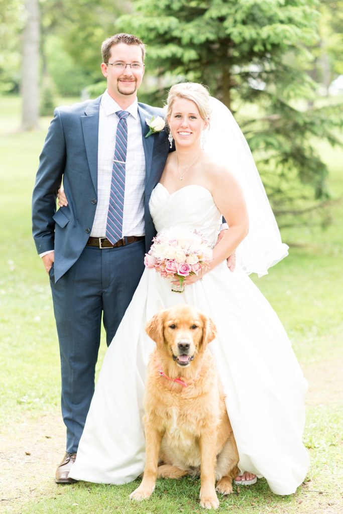 Bride and groom posing with their golden retriever