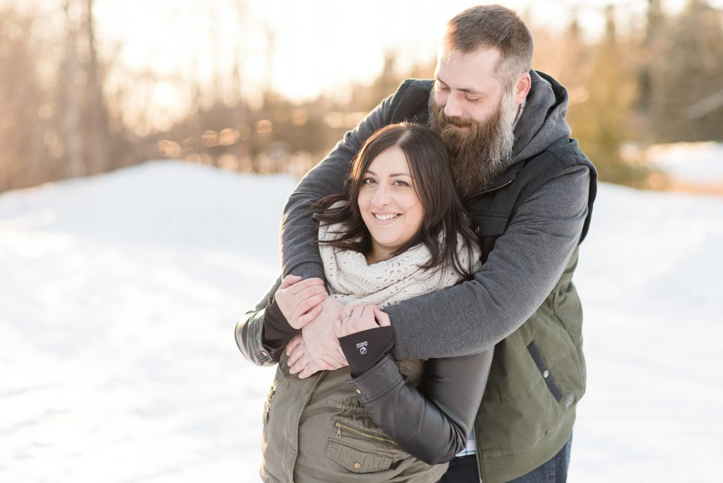 Bride and groom to be snuggle up out at Wild Goose Beach during their Thunder Bay Winter Engagement Session