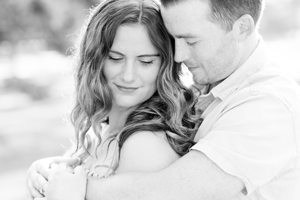 Bride and groom to be embrace during their summer engagement session at Vickers Park in Thunder Bay