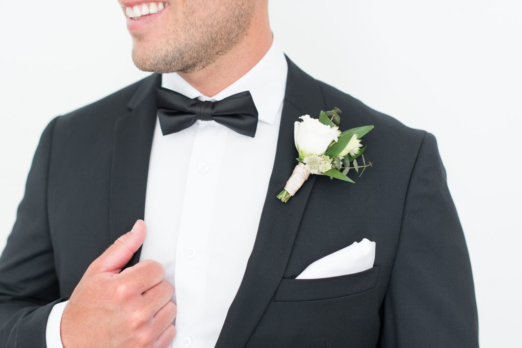 Groom showing off his boutonniere and black bow tie