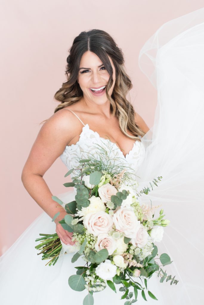 Bride shows off her beautiful Hayley Paige gown while holding soft and romantic wedding bouquet