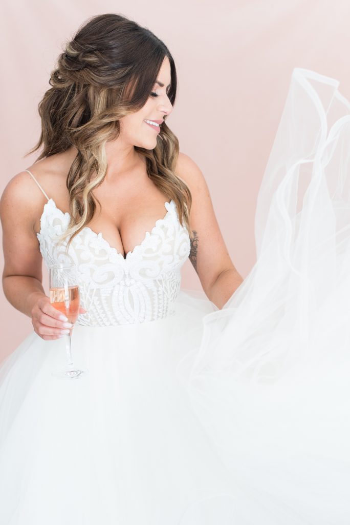 Bride shows off her beautiful Hayley Paige gown while holding a glass of rose wine