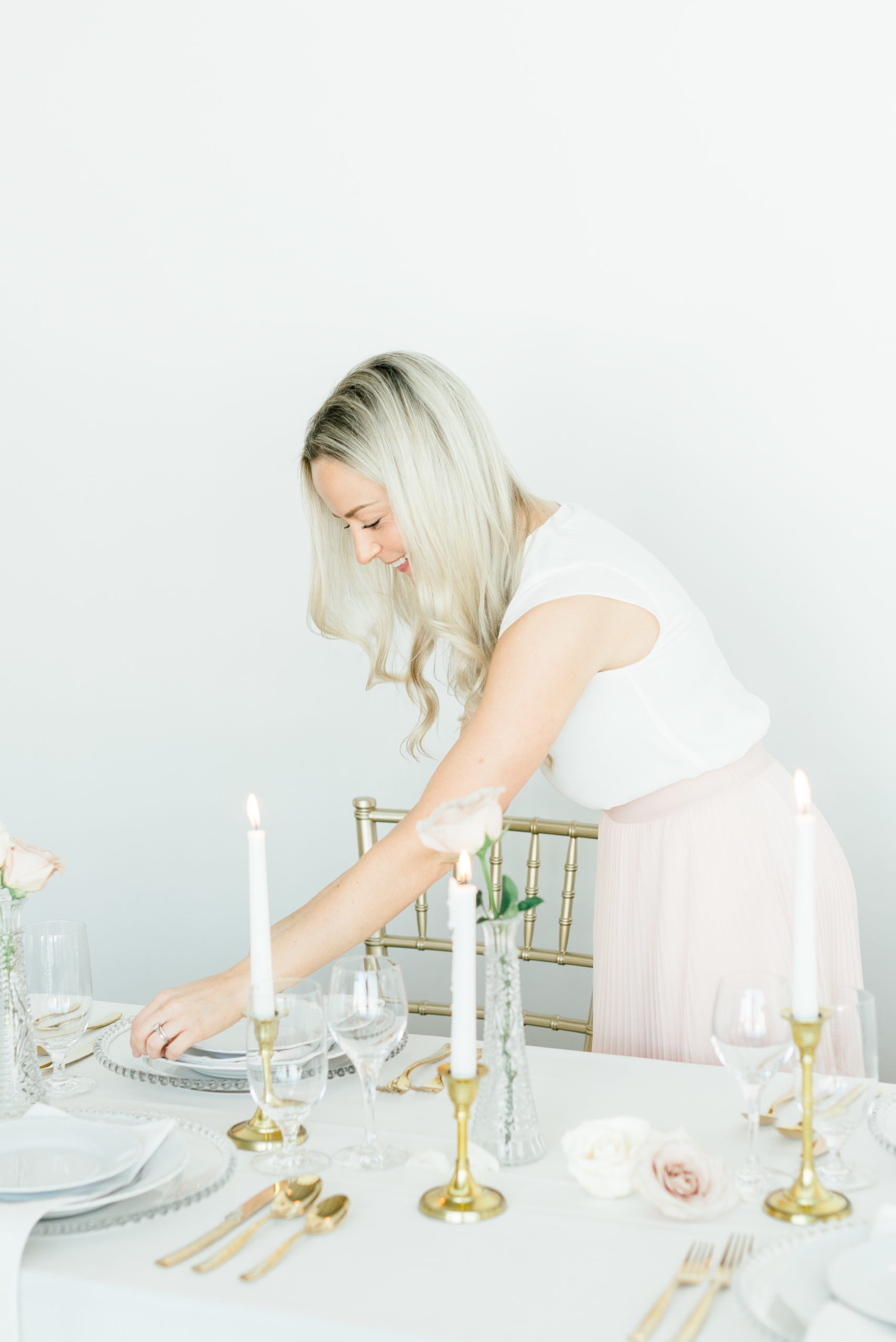 Thunder Bay wedding planner adjusting a plate on a table set with gold candles and gold cutlery