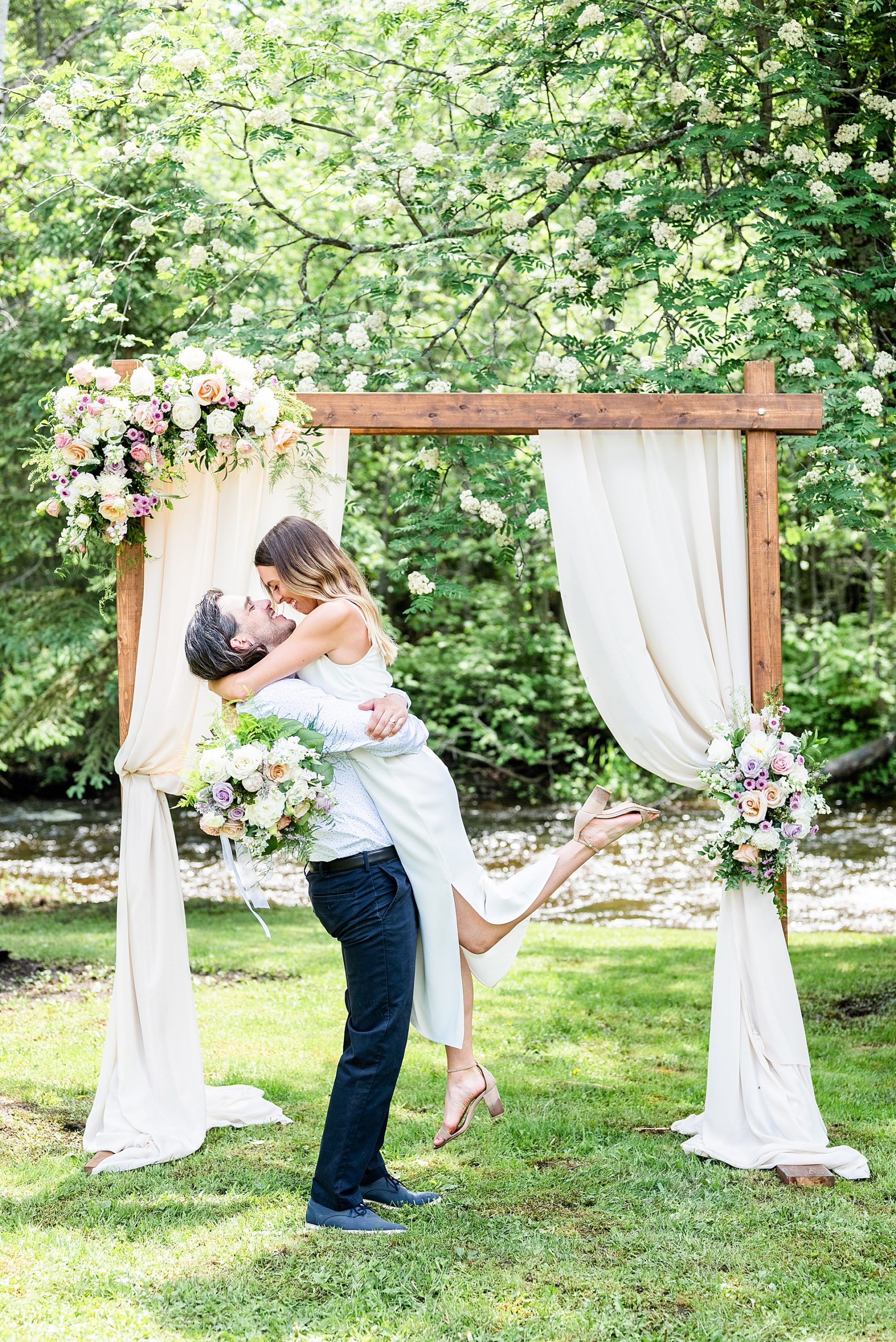 Groom lifts bride in a kiss at the alter covered in flowers