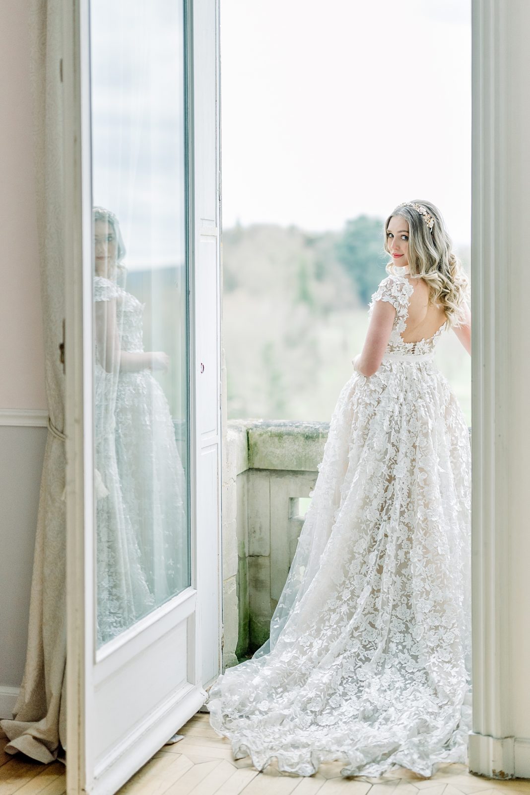 Bride standing on balcony on wedding day at Chateau Bouffemont