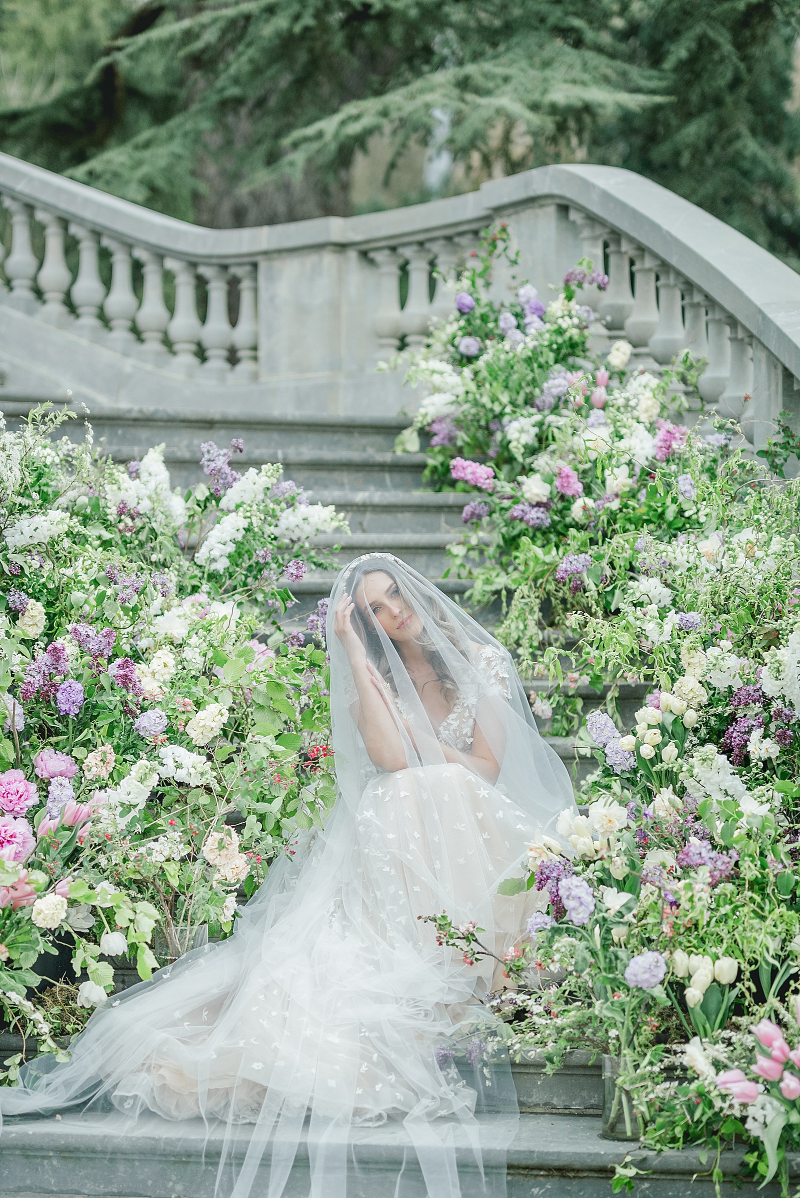 Bride sitting on flower lined staircase at Chateau Bouffemont